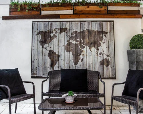 Outdoor seating area with an artistic depiction of a world map behind the table and chairs