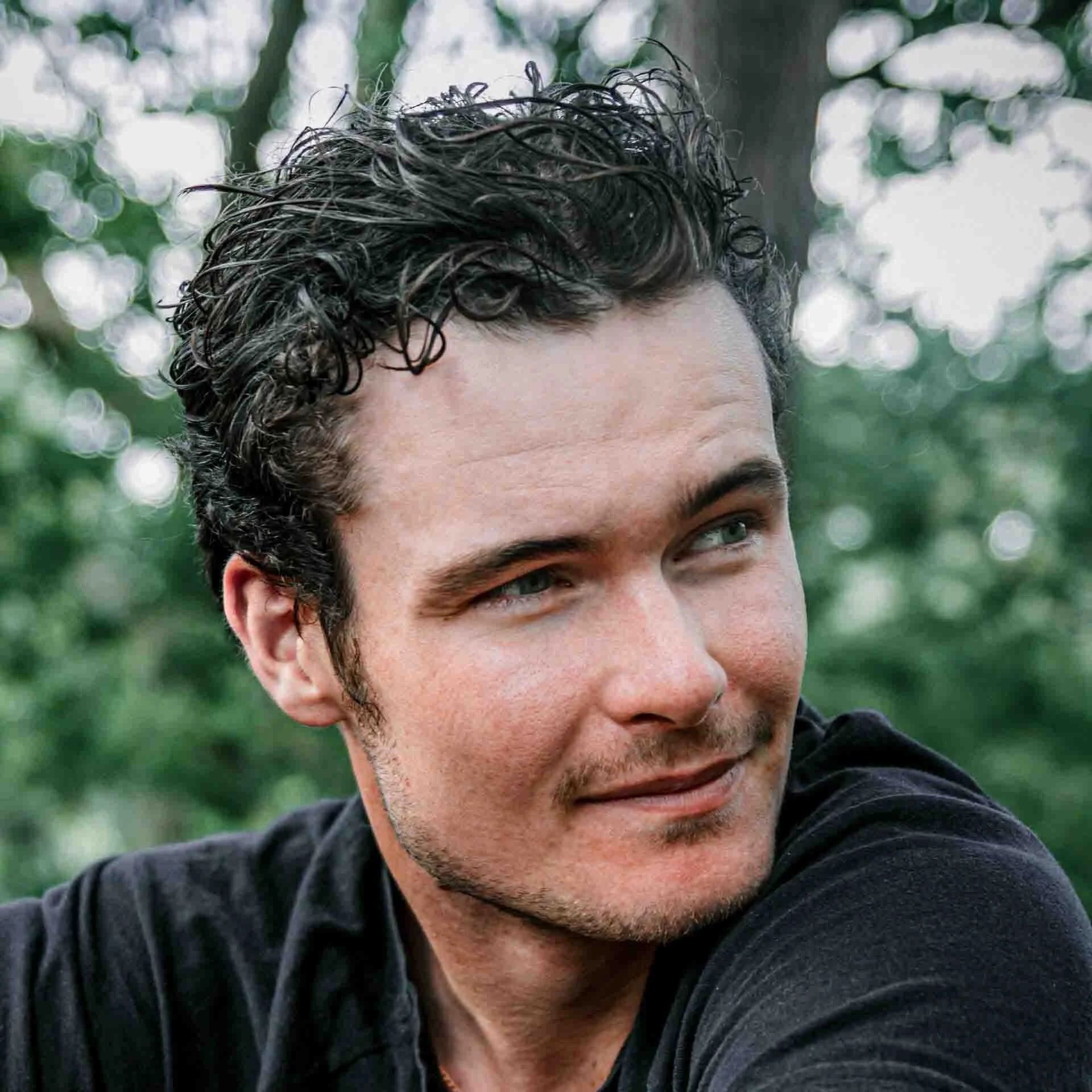 Portrait photo of Jack Chapman the founder of Create 100K looking to the side of the frame with short black hair and a black t-shirt