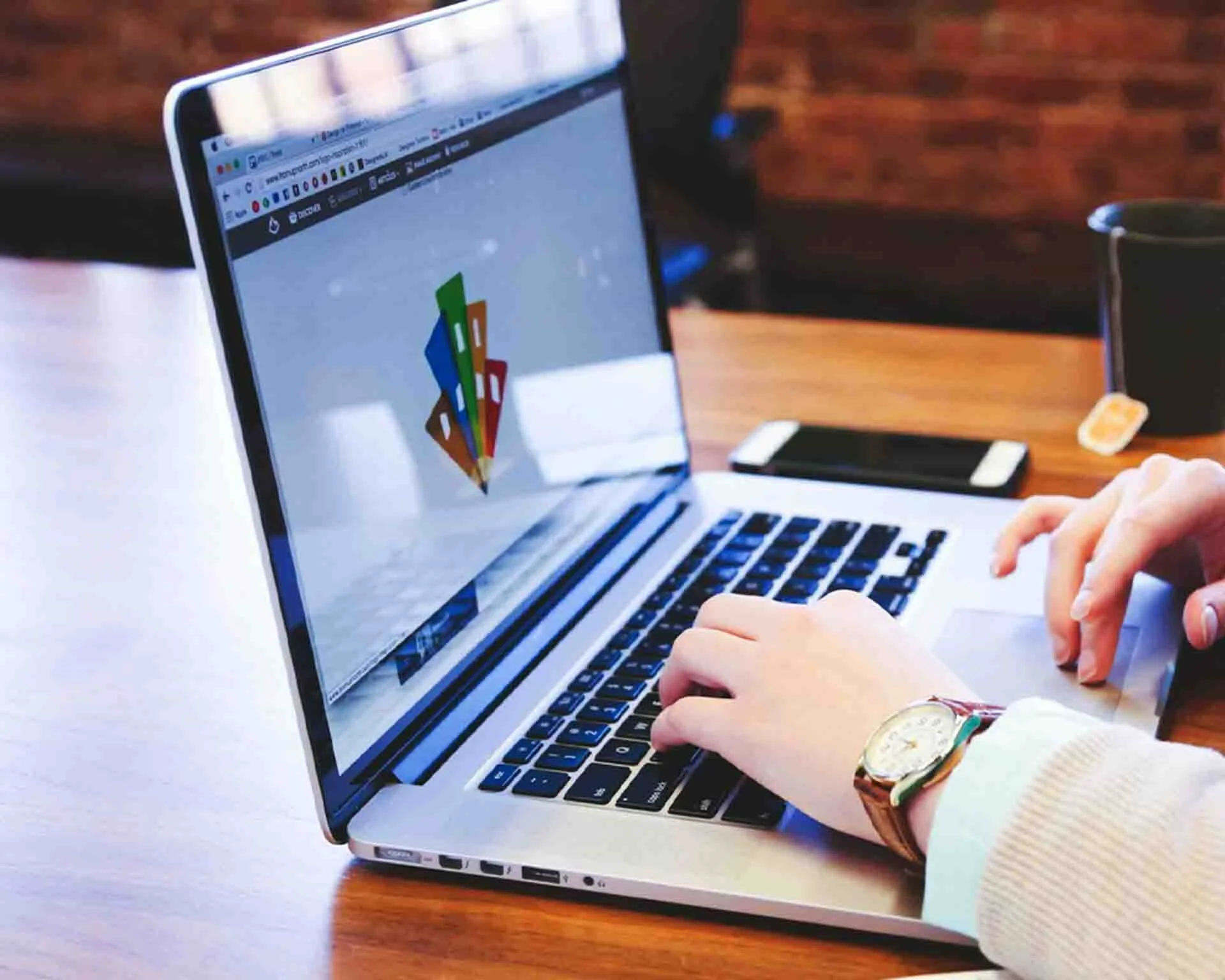A silver computer sitting on a design with someone doing some graphic design work on the screen